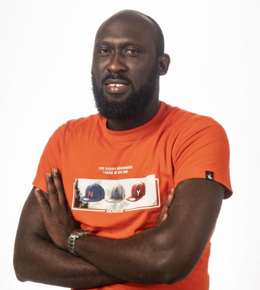 Studio portrait of bearded man with arms crossed, orange T-shirt, white background